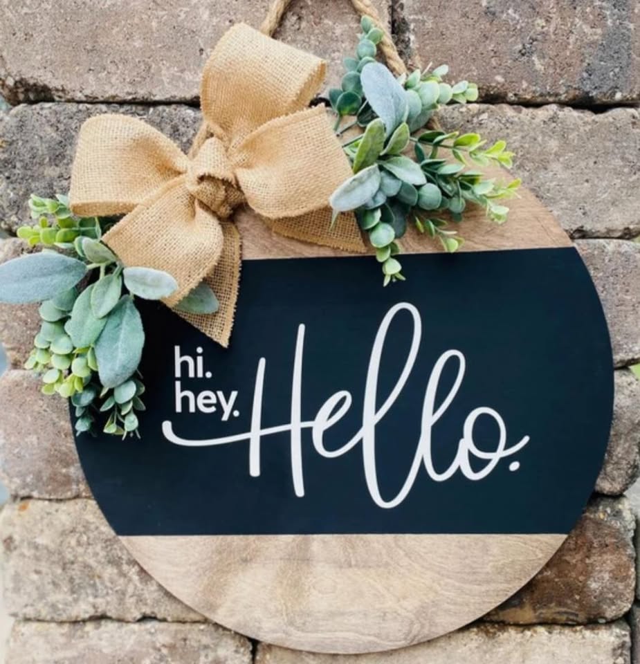 A wooden decorative hanging sign with the word Hello and ribbons.