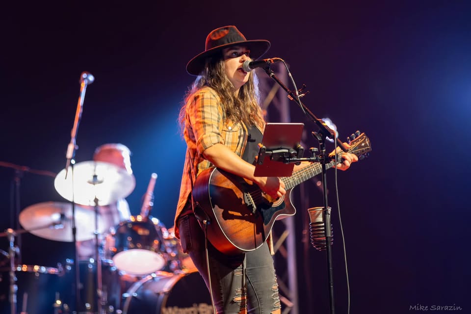 Abby Spencer sings and plays guitar on stage