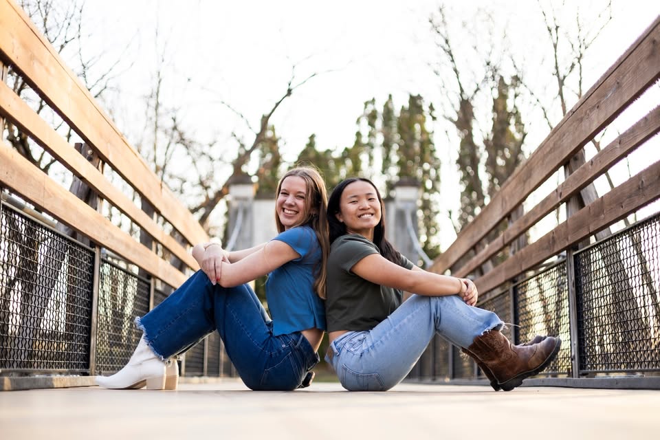 Emma and Maria sit back to back on a bridge