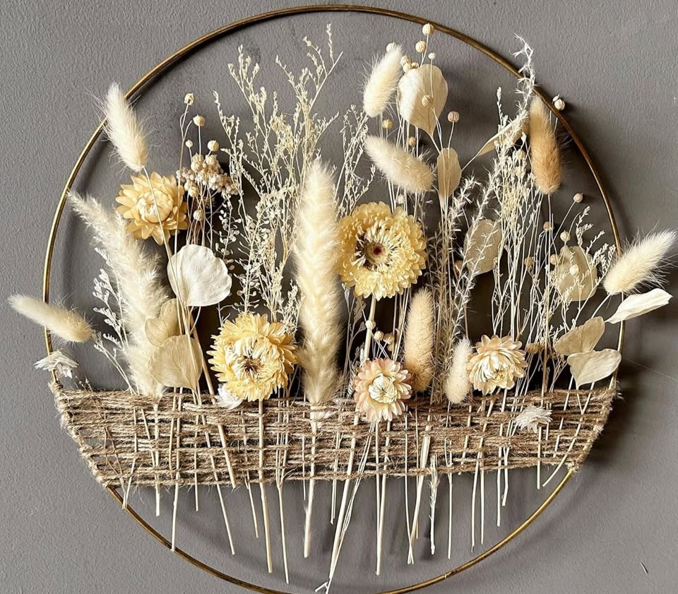 A circular metal loop with a dried floral arrangement weaved through.