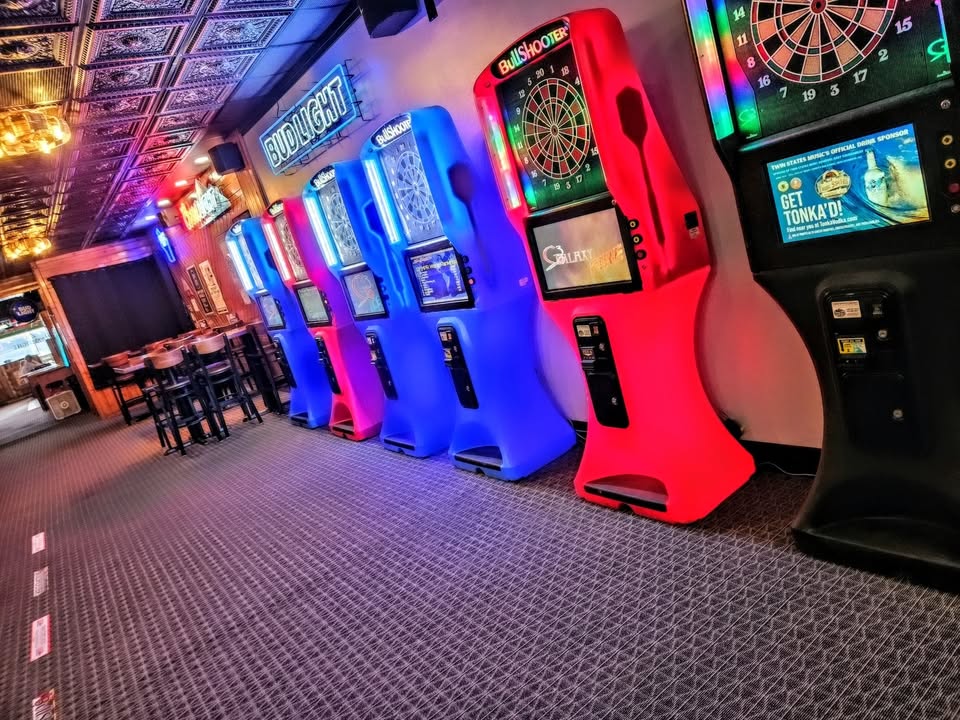 a row of dart boards in a bar with neon lights coming from them