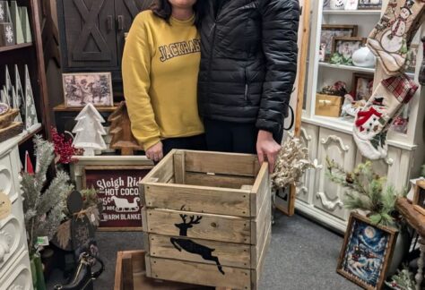 A man and woman standing behind a planter box with a deer on it.