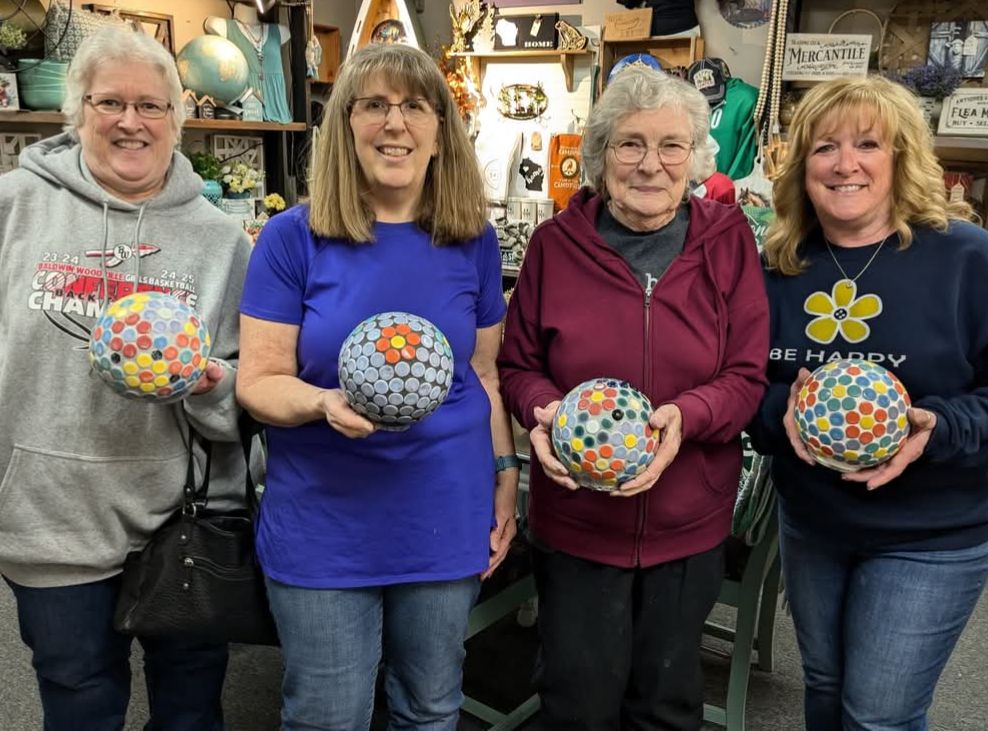 Four people holding Mosaic Gazing balls made from different colors.