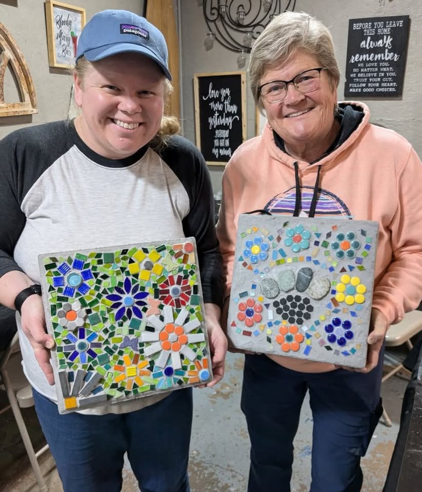 Two people holding colorful mosaic stepping stones.