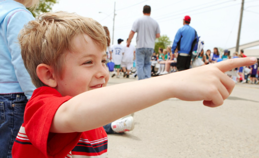 a boy points at a parade