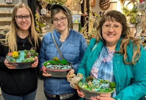 Women showing thier fairy tale gardens in containers.