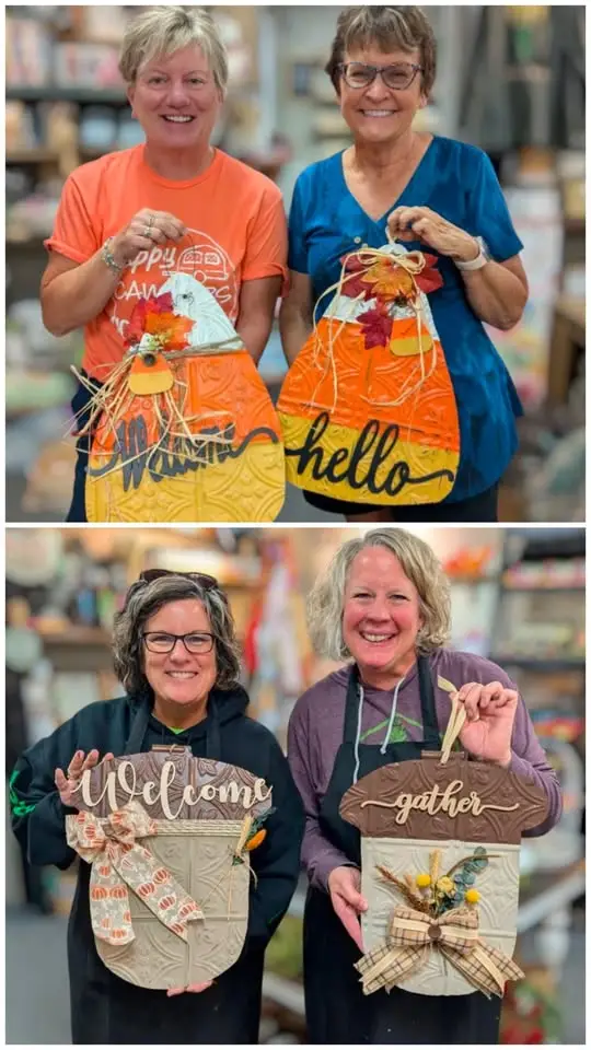 Women holding both acorn and candy corn shaped wall hangers