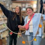 Two women hold up their fall themed beaded garlands