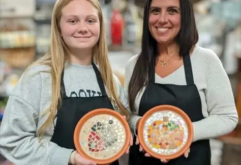 two women holding their mosaic decorative trays