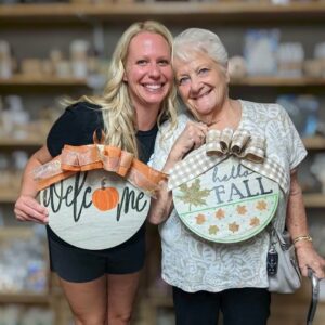 two women holding fall round wall hangs