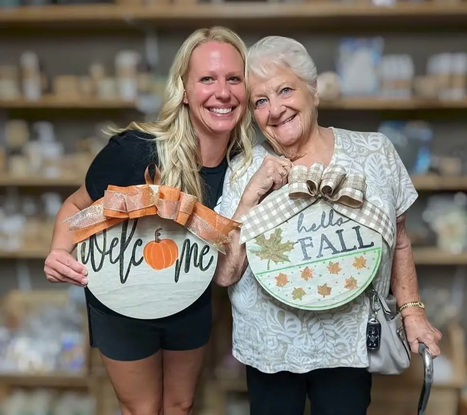 two women holding fall round wall hangs