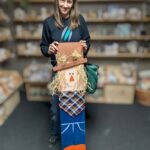 A woman stands with her wooden scarecrow