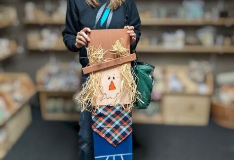 A woman stands with her wooden scarecrow