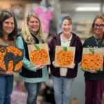 Four women hold thier halloween button art work