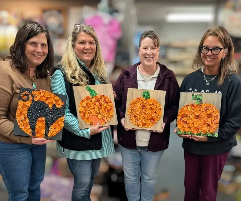 Four women hold thier halloween button art work