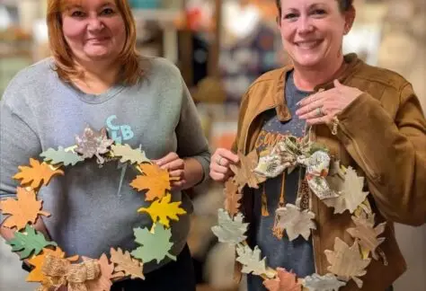 women holding their wooden leaf wreaths