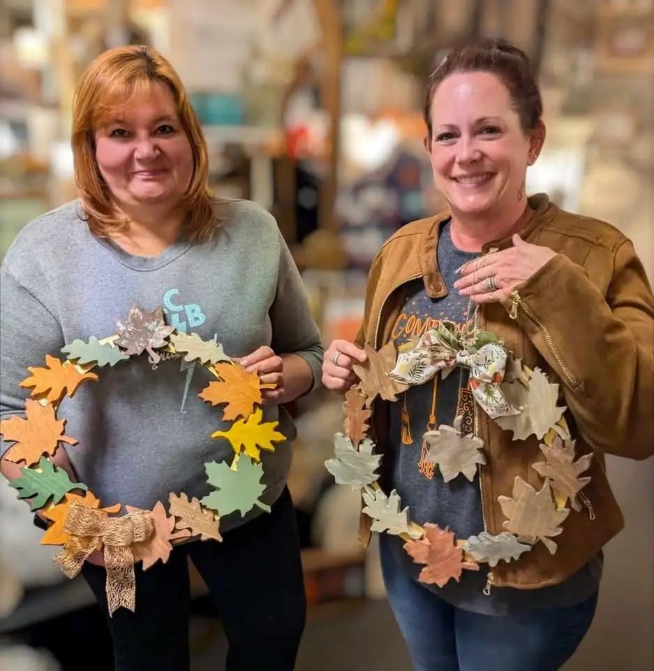 women holding their wooden leaf wreaths