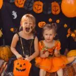 Children sitting on a car bumper with the trunk open dressed in halloween outfits